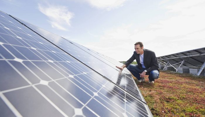 Germany, Munich, Man touching solar panel in solar plant