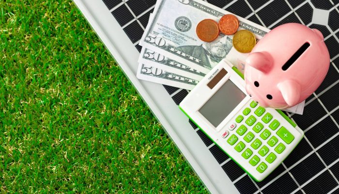 Solar panel model and piggy bank close up, energy savings concept